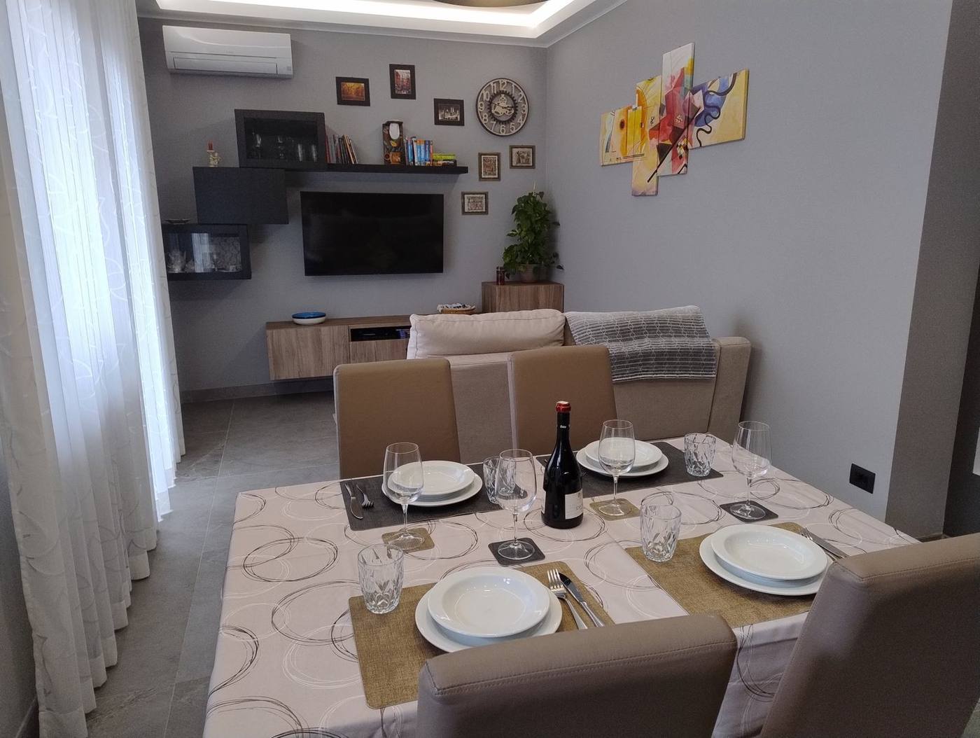 Living and dining area with set table, sofa and TV wall